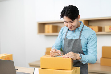 Entrepreneur packing orders. Young businessman writing shipping details on boxes in a modern...