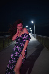 Woman in red light posing at the night pier