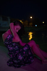 Woman in red light sitting at the night pier