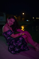 Woman in red light sitting at the night pier