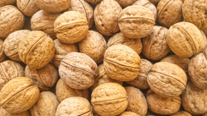 Whole walnuts in shells arranged in pile. Close-up food texture. Nut harvest and organic ingredient concept