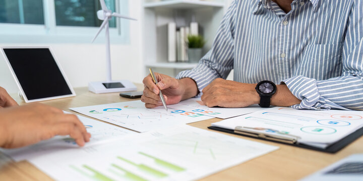 Strategic Planning. Professionals discussing ESG metrics and renewable energy strategies at a table.
