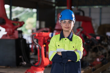 Robotic arm, Automatic robotic arm welding. Robotic manufacturing industry. Female engineer wearing safety uniform while standing with crossed arms at robotic arm repair factory