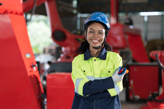 Robotic arm, Automatic robotic arm welding. Robotic manufacturing industry. Female engineer wearing safety uniform while standing with crossed arms at robotic arm repair factory - Powered by Adobe