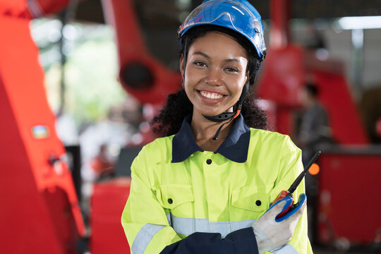Robotic arm, Automatic robotic arm welding. Robotic manufacturing industry. Female engineer wearing safety uniform while standing with crossed arms at robotic arm repair factory - Powered by Adobe