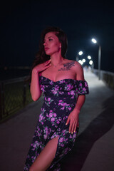 Woman in red light posing at the night pier