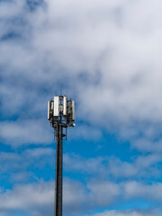 Cellular communications tower with cloud, blue sky and copy space, UK.