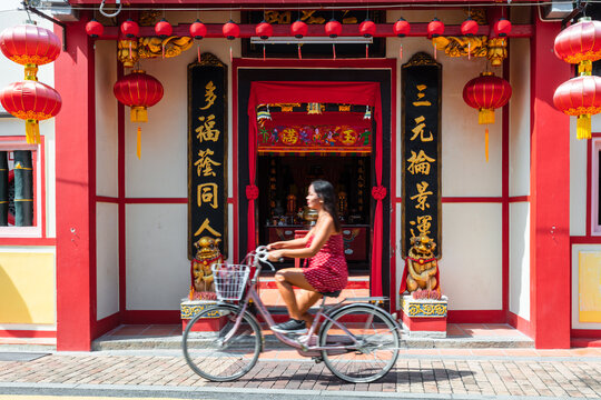 Asian tourist on a bicycle near temple, Malacca, Malaysia