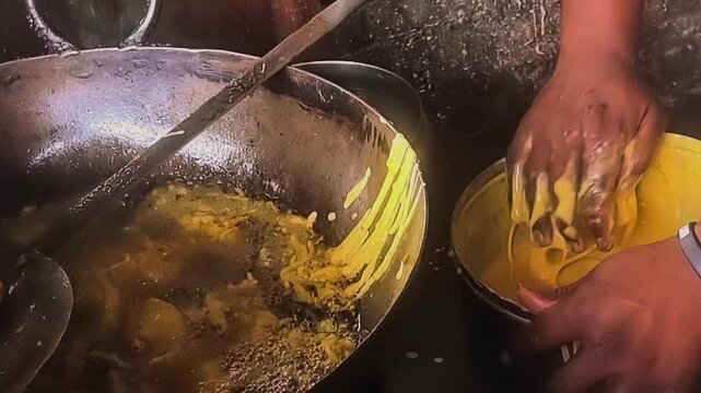 Closeup of a making vadapav by picking batata vada in hand an dip in besan batter and putting in frying pan with boiling oil. Badapaav is famous indian dish which mostly pupular in mumbai maharashtra.