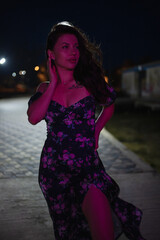 Woman in red light posing at the night pier
