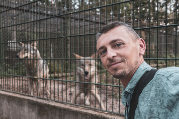 Man with dangerous Wolf behind fence in National Park Belarus. © Arkadi