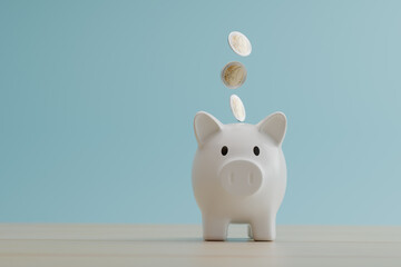 white piggy bank with coins falling on it set on blue background. financial, savings money, and...