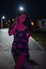 Woman in red light posing at the night pier