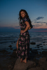 Woman in dress standing near the lake at evening