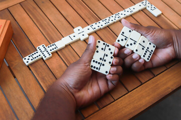 Partie de dominos en cours – mains tenant les pièces sur table en bois