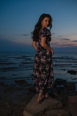 Woman in dress standing near the lake at evening