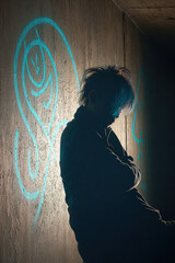 Shadowy figure leans against wall, illuminated by blue light, with graffiti art in background. scene conveys sense of mystery and urban culture, highlighting creativity and self expression