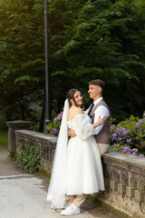 The loving groom looks at the bride with affection, hugging her around the waist. The bride came up...
