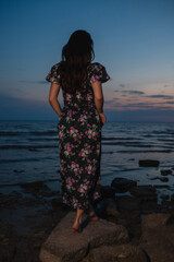 Woman in dress standing near the lake at evening