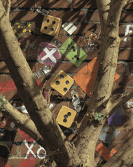 Vibrant urban scene featuring tree with branches intertwined with colorful graffiti on brick wall. artwork includes dice and various shapes, creating lively and artistic atmosphere