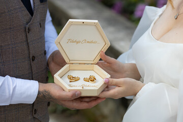 The groom and the bride are holding a personalized box with gold rings. A jewelry box with the...