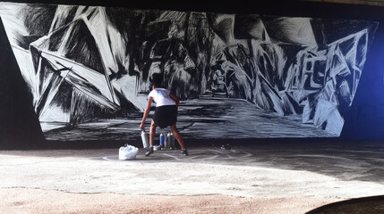 Creative urban artist is passionately spray painting large abstract mural on wall, showcasing dynamic lines and shapes. scene captures essence of street art and urban culture