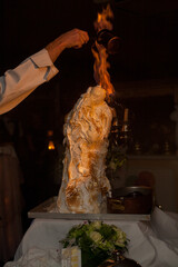 A chef performing flamb technique, igniting a creation with flames at an elegant dining setting