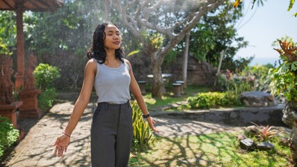 Young Asian woman practicing mindfulness and enjoying nature in a peaceful garden. A serene travel moment focused on inner peace, wellness, and connection with the environment.