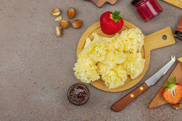 Cheese assortment on wooden boards with strawberries, nuts and jam on stone background