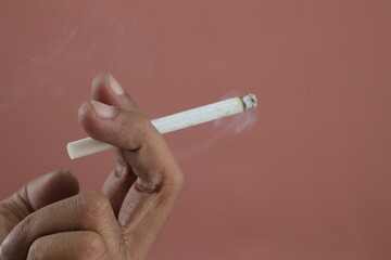 Addiction issue - Close up of a hand holding a burning cigarette, Cigarette in a fingers.
