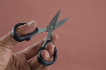 Stylish man hand holding scissors on isolated background. Man's hand holds scissors isolated on...
