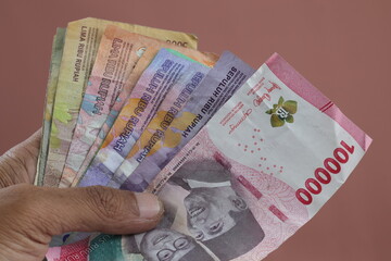 Male hand holds Indonesia rupiah for financial income or online service on isolated background. Arm holding a lot of money,  big profit.
