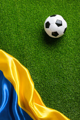 A soccer ball on a green field with a Ukrainian flag. High quality photo