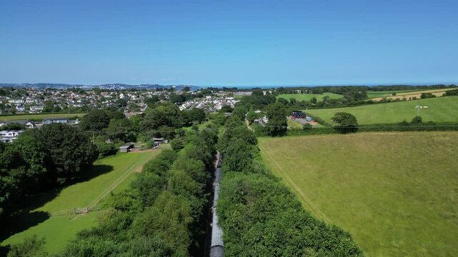 Churston, South Devon, England: DRONE VIEWS: A steam train on route from Kingswear to Paignton; the sea of Torbay is in the distance. South Devon is a popular UK holiday destination (Clip 1 of 2).
