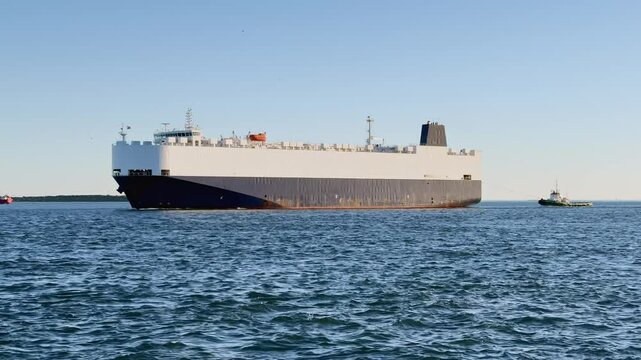 Vehicle carrier or RO-RO ship sailing with tugboat into port