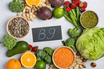 Top view of foods rich in vitamin B9 (folic acid) with vegetables, legumes, fruits and seeds. Healthy lifestyle and nutrition concept on light background.