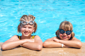 Portrait smiling girl and boy in swimming pool, two children in swimming glasses. Summer travel hotel vacation or classes. Kids relaxing in pool, swimming in blue water. activity, watersports.