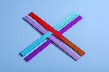 Colorful wooden sticks forming an X shape on a pastel background