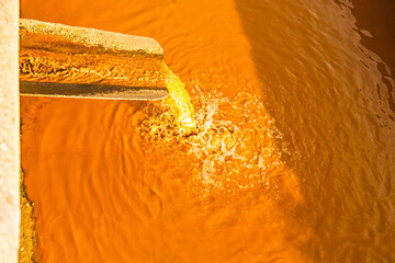  dirty orange water flows down the pipe. Dirty water discharge. water pollution. environmental...