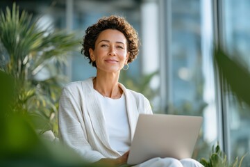 Elegant businesswoman in white outfit working on laptop in bright modern office