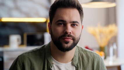 Obraz premium Portrait calm relaxed European Caucasian young adult bearded man male guy homeowner model businessman look distance thinking looking at camera domestic relaxation weekend indoors home room apartment