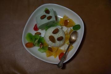 Ice cream dessert with fruits prepared at home in the form of funny smiley faces, eyes and mouth made from almonds.