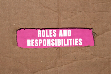 Roles and responsibilities message written on ripped torn cardboard paper on pink background. Conceptual roles and responsibilities symbol. Copy space.