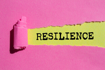 Resilience message written on ripped torn pink paper on yellow background. Conceptual resilience...