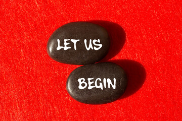Let us begin message written on black stones on red background. Conceptual let us begin symbol. Copy space.