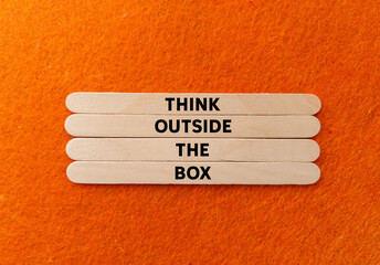 Think outside the box message written on wooden sticks on orange background. Conceptual think...