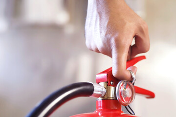 Closeup of a male hand pulling the safety pin of a manual chemical Fire extinguisher available in...