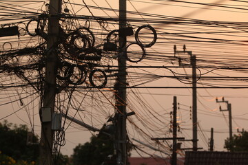 Tangled Electrical Mess: A chaotic web of tangled electrical wire stretches across a city street,...