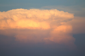 Pink Sunset Cloudscape: A towering cumulus cloud, dramatically lit by the setting sun, paints the sky with vibrant pink and orange hues during sunset.