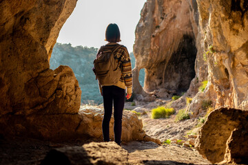 girl with a backpack. A woman with a backpack stands in a cave. The girl explores the cave. Tour of the cave.
